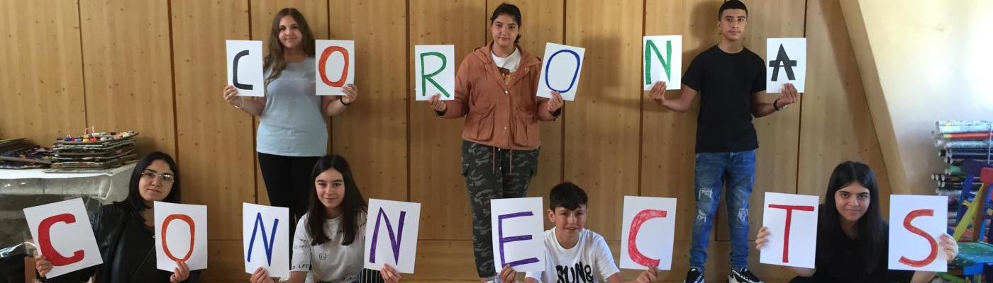7 Schülerinnen und Schüler halten Zettel mit den Buchstaben für die Wörter "Corona Connects" in die Höhe